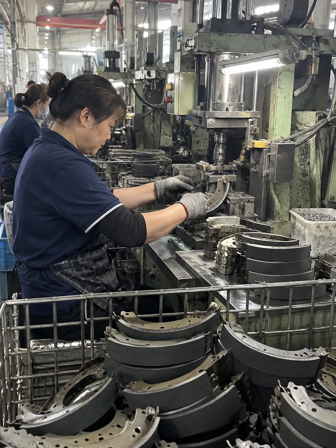 Remskoenvervaardiger se produksielyn: werker wat dromremskoene in ons Qingyuan-fabriek pers