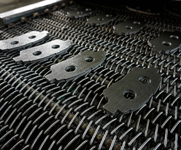 Brake pad backplate on a woven conveyor belt